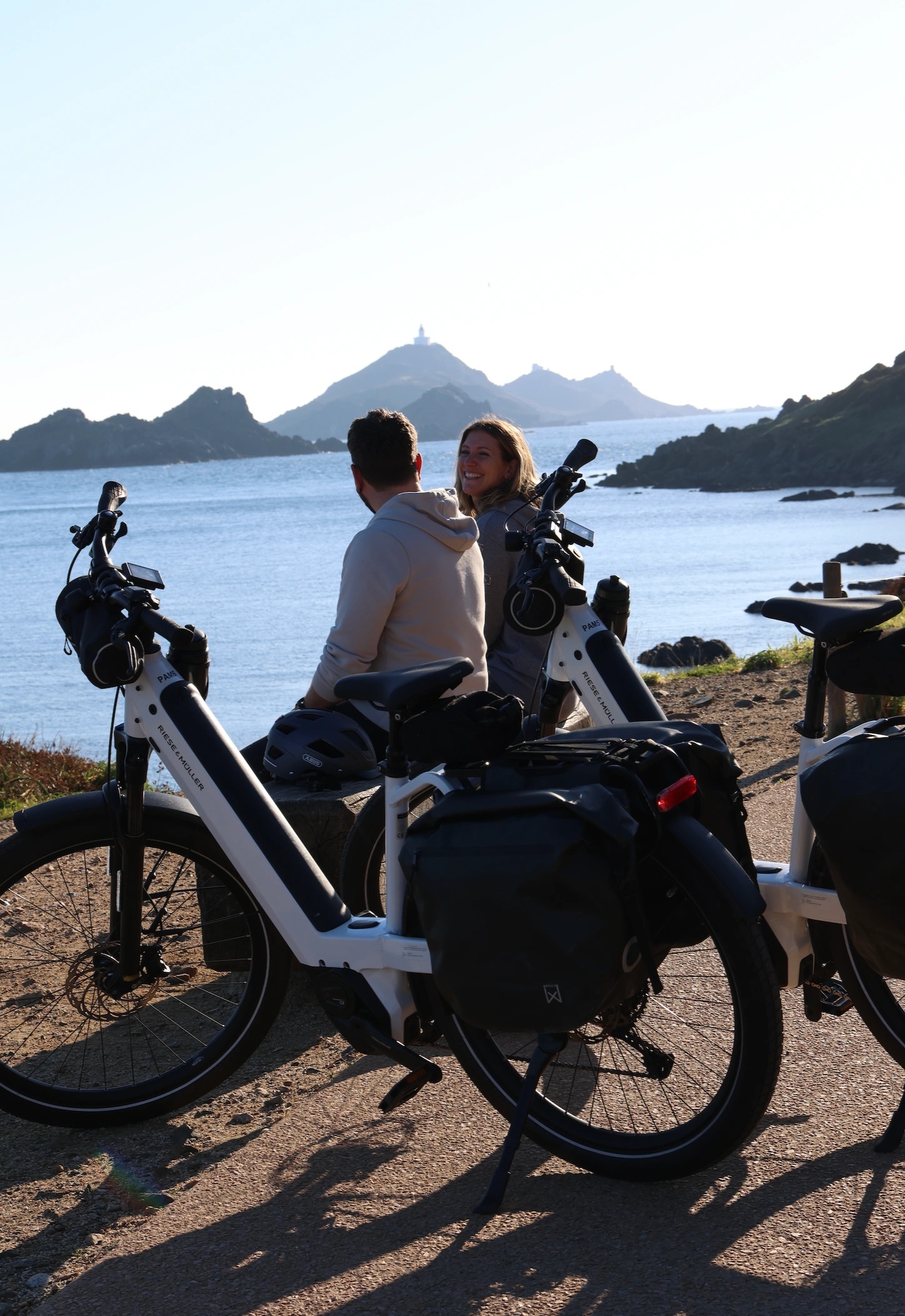 Deux voyageurs admirant le coucher de soleil sur les montagnes et la mer en Corse